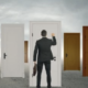 Businessman standing in front of multiple doors, symbolizing choices and opportunities, highlighting how Dallas IT Consulting helps businesses choose the right path for growth and success.